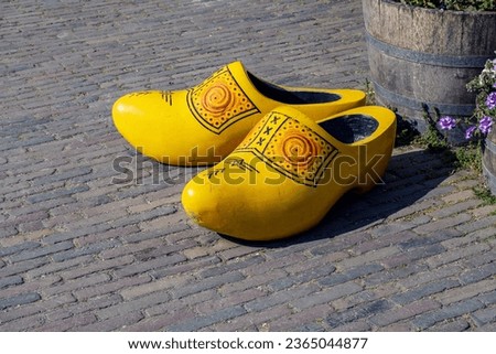 Wooden clogs, coloured in yellow, carved from solid wood placed on the floor as photo site at the village of Zaanse Schans, Netherlands