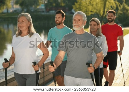 Group of people practicing Nordic walking with poles outdoors on sunny day Royalty-Free Stock Photo #2365053923