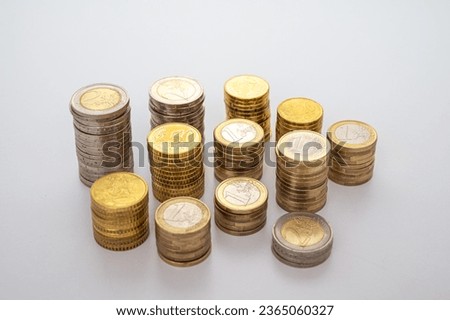Stacks of coins next to each other, on white surface. Quantity of money, currency and wealth.