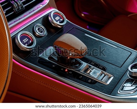 gear lever and climate control with temperature indicators with pink ambient lighting in a leather interior in a luxury car