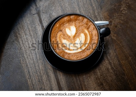 Hot coffee latte with latte art milk foam in cup mug on wood desk on top view. As breakfast In a coffee shop at the cafe,during business work concept,vintage style