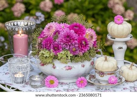 romantic flower arrangement of pink dahlias in vintage soup tureen, white pumpkins and table lanterns Royalty-Free Stock Photo #2365080171