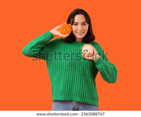 Young woman with pumpkins on orange background