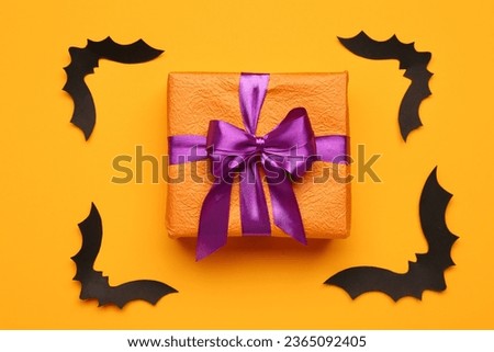 Paper bats for Halloween party and gift box on orange background