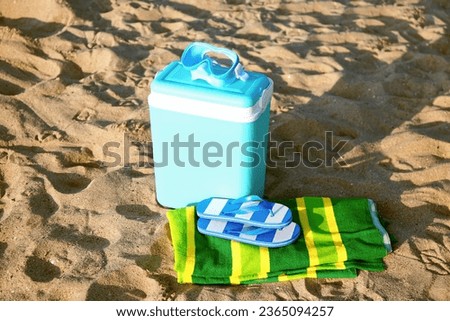 Beach cooler and accessories on sand