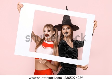 Female friends dressed for Halloween with frame on pink background