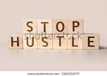 The word STOP HUSTLE on cubes on a beige studio background. Copy Space. Written. Text words matter. Conceptual Image. Concept of maintaining mental health while working overtime. Don't work long hours