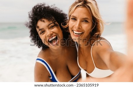Two friends, brimming with energy and laughter, embark on a beach adventure filled with excitement. In the midst of their joyful beach activities, they pause to capture the moment with a selfie.
