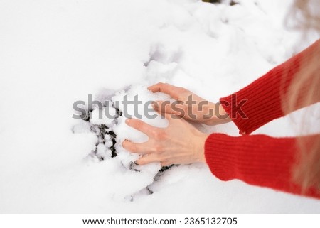 Close-up of a young woman's hands forming a snowball for playing and having fun. Concept of winter holidays and activities
