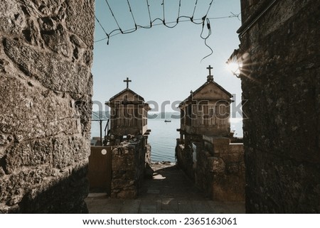 Two traditional granaries in Combarro, the sea on the background