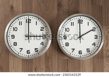 Two clocks, one showing three o'clock, the other showing two o'clock. Time change symbol. Moving the hands backward in autumn to normal time. Royalty-Free Stock Photo #2365163139