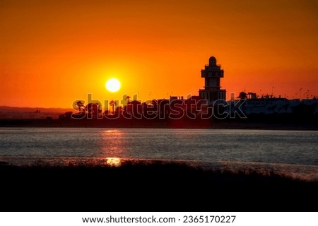 Beautiful orange sunset panorama at the harbor of Isla Cristina, Costa de la Luz, Spain, with the lighthouse as a silhouette
