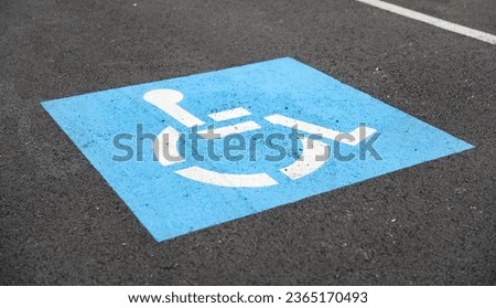 blue handicap parking symbol against asphalt background, representing accessible spaces for disabled individuals, inclusivity, and equal rights Royalty-Free Stock Photo #2365170493