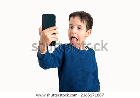 Showing his silly side. Cropped shot of a child sticking his tongue out while taking a selfie with white background