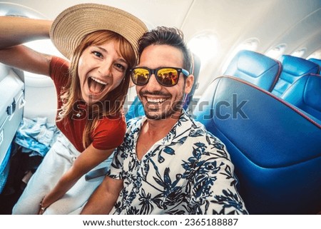 Happy tourist taking selfie inside airplane - Cheerful couple on summer vacation - Passengers boarding on plane - Holidays and transportation concept Royalty-Free Stock Photo #2365188887