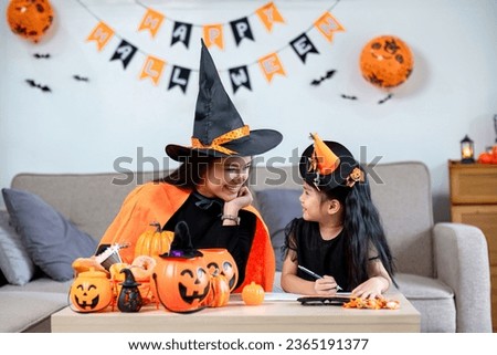 Family mother and daughter prepare decorations for Halloween at home. Draw pictures and cut paper together. and participate in creativity