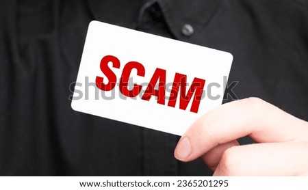 Businessman holding a card with text SCAM ,business concept