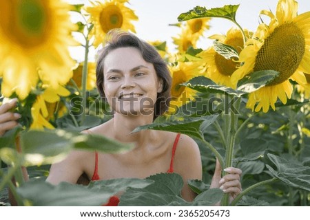 Woman in Sunflower Field: Happy girl in a straw hat posing in a vast field of sunflowers at sunset, enjoy taking picture outdoors for memories. Summer time