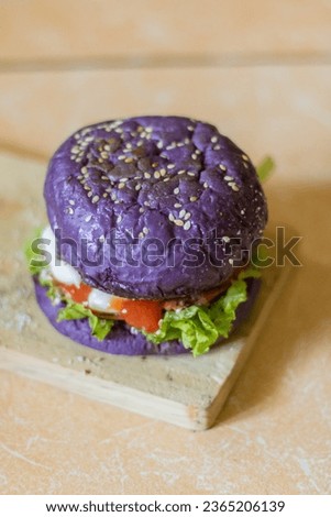 close up photo of a home-made purple burger placed on a ceramic table. Hamburger. Fast Food. Culinary