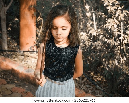 Indian little girl playing. outdoor in park. dark and light portrait filter effect image.Wearing black and white. clothes with comedy action.Blur background photo using for wallpaper.