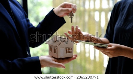 Male businessman or real estate agent holding house key for his client after signing contract in office.