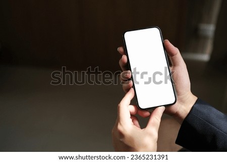 Close-up of male hand holding smartphone with white mockup on screen.