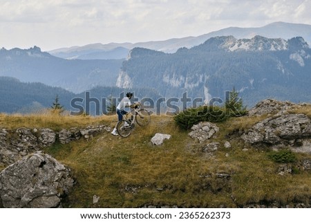Fit male cyclist is going to ride on dirty gravel road a gravel bike in the beautiful mountains. Cyclist is practicing on gravel road. Sports motivation.Gravel road in mountains.
