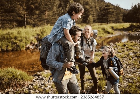 Young family crossing a creek while hiking in the forest and mountains Royalty-Free Stock Photo #2365264857