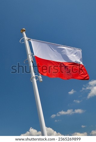 White and red flag Polish waving in the wind against the blue sky
