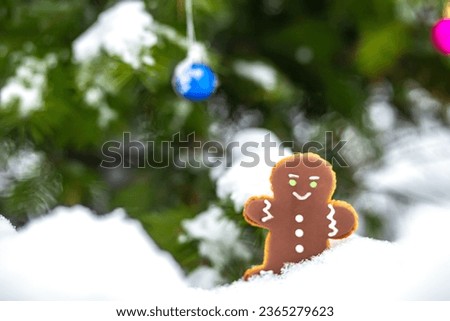 Gingerbread figures on the background of a snowy scene, next to a beautifully decorated Christmas tree.
