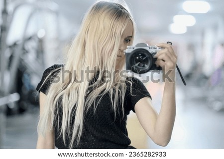Young girl with camera in hand stands in front of the mirror, takes a selfie, A young woman takes herself to the camera through a mirror, she enjoy taking pictures of themselves.
