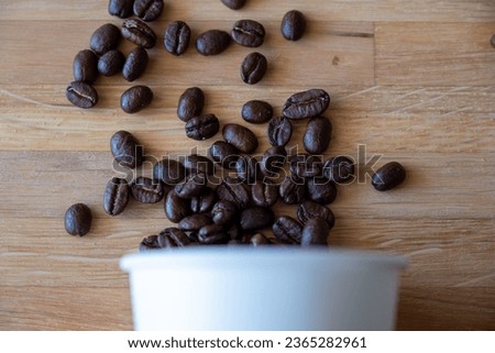 Paper cup of coffee and coffee beans on wooden background with mockup space for copy and creativity