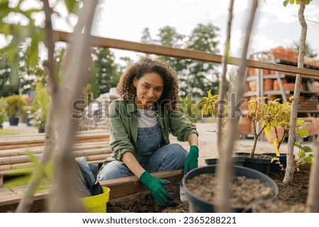 Professional woman garden worker transplants plants and takes care of flowerpots in botanic shop