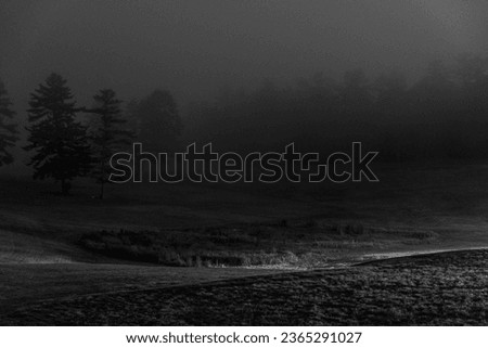 A foggy lanscape with a small single line of light passing through its middle