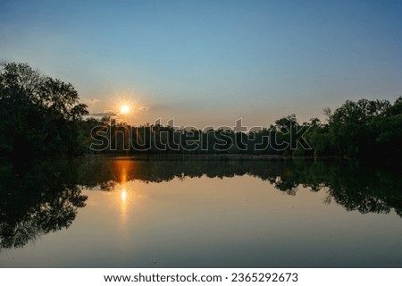 pond at sunset landscape reflection of sun and trees