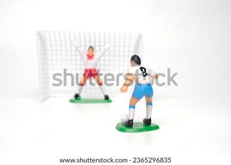 Selective focus picture of football kicker miniature trying to pull a shot on white background