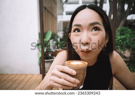 Asian woman sipping hot coffee in cafe