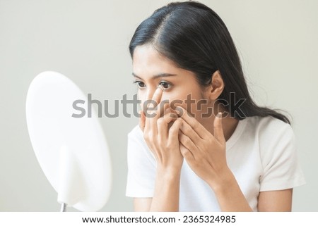 Ophthalmology care, eye sight, vision concept. Asian young woman, female hand holding and putting, wearing soft contact lenses with finger on face, girl looking in mirror at home. Medicine and health. Royalty-Free Stock Photo #2365324985