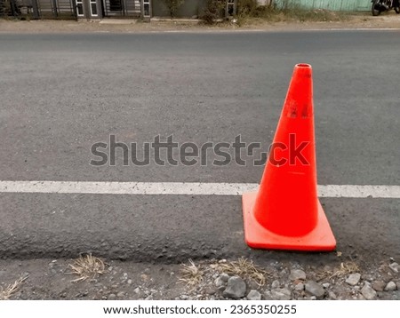 the red cone at street, traffic marking device, in the form of a red cone, placed on the edge of the asphalt road, indicating the boundary, which cannot be violated or passed by vehicles, apil cone
