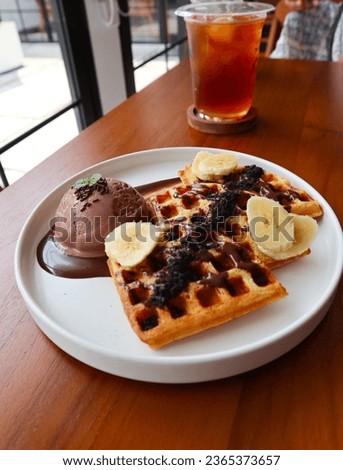Plate of delicious Chocolate Belgian Waffles with ice cream and banana on wooden table