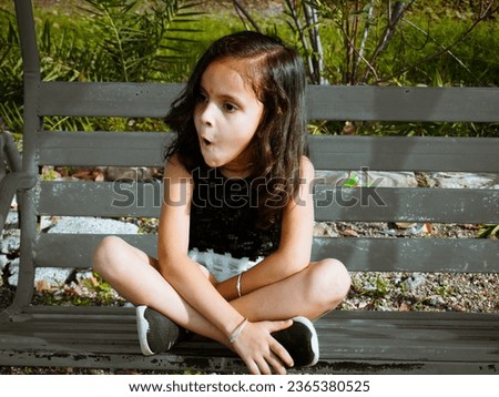 Little cute girl swinging in park.Different pose with filter effect on camera raw photo.Light and dark preset editing.Kid girl sitting on bench.