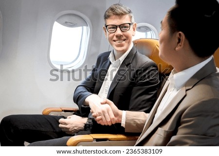 Businessman making handshake in comfortable seat inside airplane male passenger handshaking after good deal during business trip in aircraft cabin, businesspeople traveling with airline transportation Royalty-Free Stock Photo #2365383109