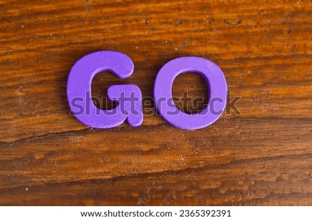 GO word made of colored wooden letters, wooden table background. Learn the English alphabet. Concept of child education, school, kindergarten, preschool