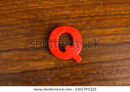 The word "Q" made of colored wooden letters, wooden table background. Learn the English alphabet. Concept of child education, school, kindergarten, preschool