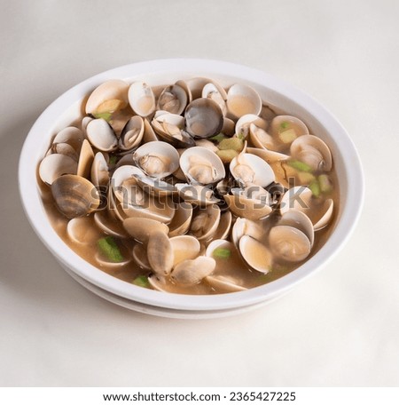 braised fresh White Sea clam shell in Chinese wine herbal ginger onion sauce and scallion soup in white plate on tea pot wood table asian restaurant banquet cuisine halal food menu