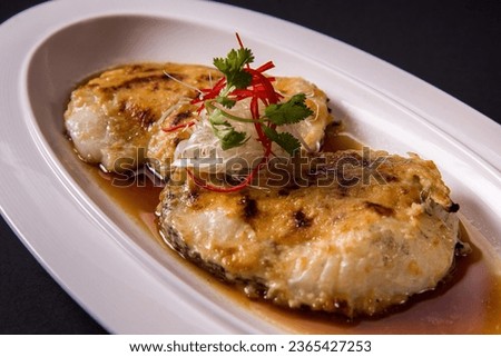 local steam grilled bbq cook live fresh chilean seabass cod fish fillet seafood in Hong Kong style soy sauce on black table asian restaurant banquet cuisine halal food menu