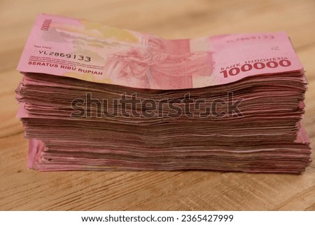 stacks of one hundred thousand rupiah or 100,000 bills on a wooden table. Indonesian currency. IDR. economy concept. 
