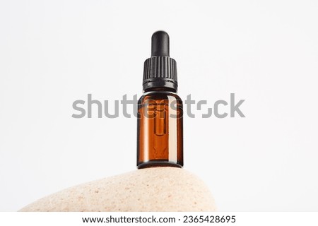 Brown dropper bottle without label is on light stone. Royalty-Free Stock Photo #2365428695