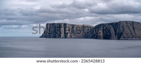 View from  at the North Cape which is the northmost point of European continent. Massive cliff over 300m high. Image from distance looking at the peninsula. Early summer in Norway. Calm sea allaround