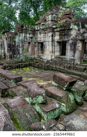 Moss covered green stone temple exterior and bricks wall at the Ta Prohm Tomb Raider Temple complex ruins in Angkor Wat historical site, Seim Reap, Cambodia Royalty-Free Stock Photo #2365449861
